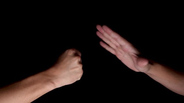 Two Hands Playing Rock, Paper, Scissors Against Black Background. Locked Off 