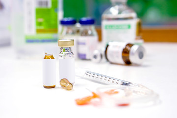 Sample vials and plastic syringe with 3 ml. ampule is opened on white table with ampule blurry background.