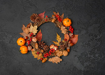 autumn Thanksgiving wreath with pumpkin, fall leaves, red berries, acorns on dark background. autumn holiday, fall, thanksgiving, halloween concept. Flat lay, top view, copy space © Ju_see