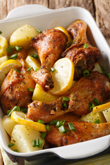 Baked chicken legs with lemon and boiled potatoes close-up in a baking dish. vertical