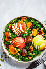 Winter salad with apple, pumpkin, cranberries, honey and seeds in white plate, top view. Healthy vegan food concept.
