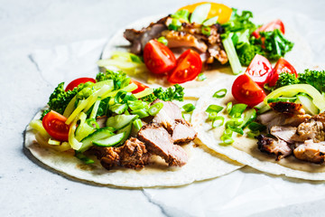 Healthy mini tortillas with grilled chicken, meat, fresh vegetables  on light grey background.