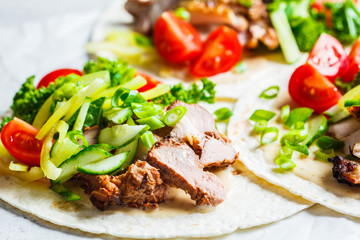 Healthy mini tortillas with grilled chicken, meat, fresh vegetables  on light grey background.