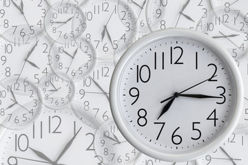 White analog round office clock on the background of a set of clocks f different sizes showing various time