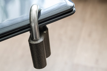 Locked steel padlock in a drilled hole of the black laptop. Concept of protecting personal data on a computer. A laptop is locked with a lock. Closeup, selective focus