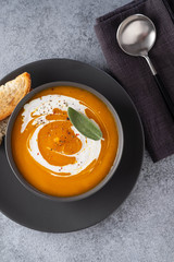 Pumpkin soup with sage on grey background. Top view.