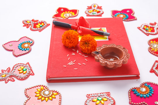  Red accounting note book , diya, and flower rangoli on white background