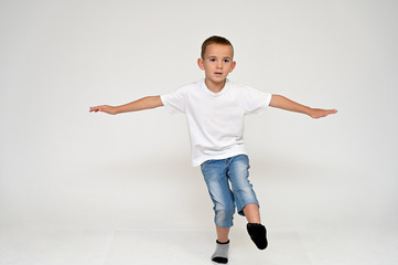 Fototapeta na wymiar Full-length portrait on a white background of a cute boy child with Vitiligo disease - a violation of the color of the skin at the initial stage. White T-shirt, blue jeans.