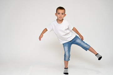 Fototapeta na wymiar Full-length portrait on a white background of a cute boy child with Vitiligo disease - a violation of the color of the skin at the initial stage. White T-shirt, blue jeans.