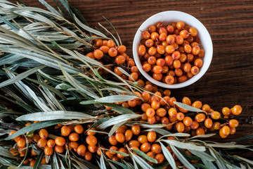  Leaves and berries of orange sea ​​buckthorn on wooden table background