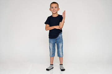 Full-length portrait on a white background of a cute boy child with Vitiligo disease - a violation of the color of the skin at the initial stage. Black T-shirt, blue jeans.