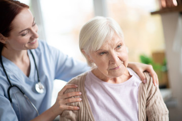 Smiling caregiver doing massage for retired woman