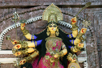 Goddess Durga idol at decorated Durga Puja pandal, shot at colored light, at Kolkata, West Bengal,...