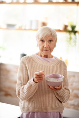 Woman in warm sweater eating oats in the morning