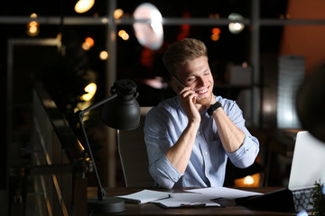 Young man working in office at night. Space for text
