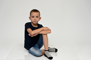 A full-length portrait of a cute boy child sitting on the floor on a white background with Vitiligo...