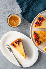 Classic cheesecake with berries and cup of espresso on gray background. Top view.