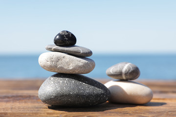 Fototapeta na wymiar Stacks of stones on wooden pier near sea. Zen concept