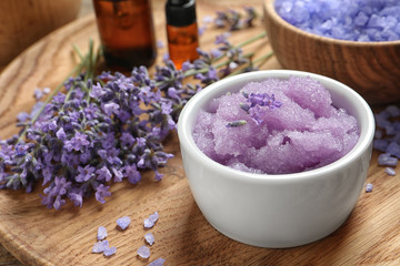 Obraz na płótnie Canvas Bowl of natural sugar scrub and lavender flowers on wooden plate. Cosmetic product