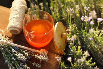 Jar of honey on wooden table in lavender field. Space for text