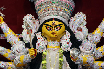 Goddess Durga idol at decorated Durga Puja pandal, shot at colored light, at Kolkata, West Bengal,...