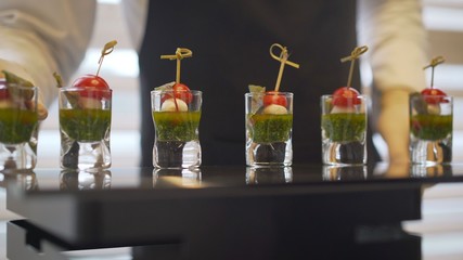 off-premise catering - waitresses put fruit canapes on buffet table. Catering. The waiter lays out snacks.