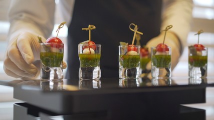 off-premise catering - waitresses put fruit canapes on buffet table. Catering. The waiter lays out snacks.