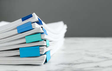 Stack of documents with binder clips on marble table against grey background, closeup. Space for...