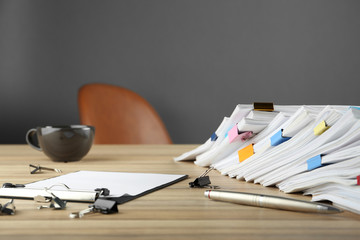 Stack of documents with binder clips on wooden table