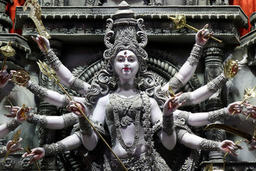 Goddess Durga idol at decorated Durga Puja pandal, shot at colored light, at Kolkata, West Bengal,...