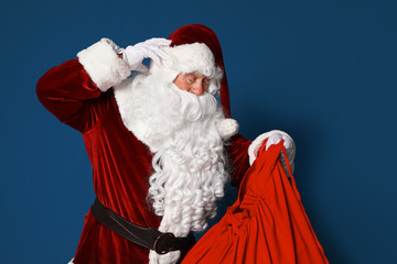 Authentic Santa Claus with bag full of gifts on blue background