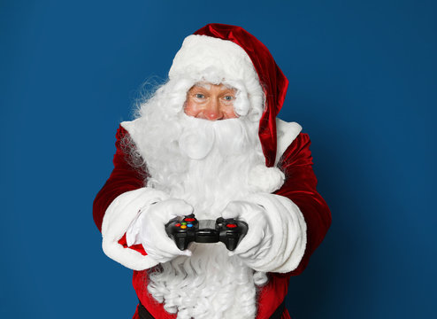 Authentic Santa Claus with game controller on blue background