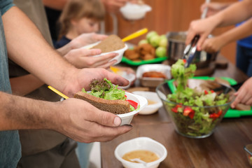 Poor man holding plate with food in charity centre, closeup