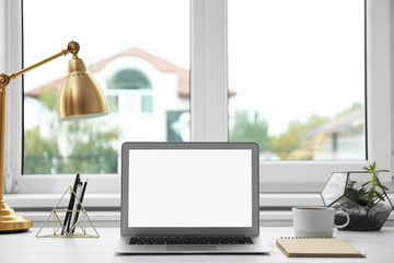 Fototapeta premium Modern laptop on desk near window at home