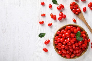 Flat lay composition with fresh ripe goji berries on white wooden table. Space for text