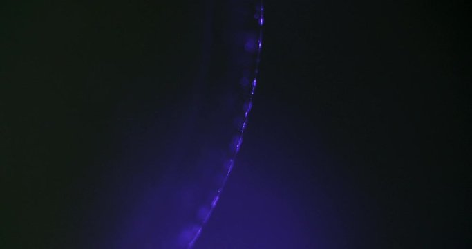 macro shot of a stream of puple particles moving in the dark on a vertical sphere in a universe like surrounding.