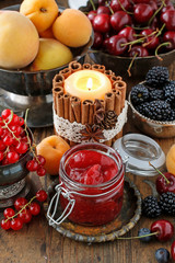 Jar of strawberry jam among summer and autumn fruits