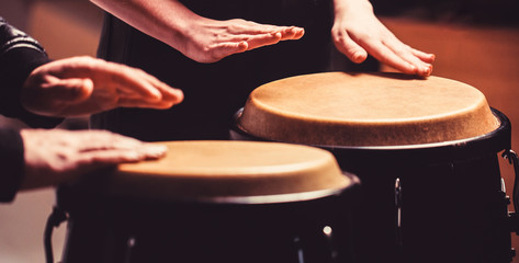 The musician plays the bongo. Close up of musician hand playing bongos drums. Afro Cuba, rum, drummer, fingers, hand, hit. Drum. Hands of a musician playing on bongs.