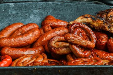 Close up. Sausages are grilled and stacked in a large cast-iron pan.