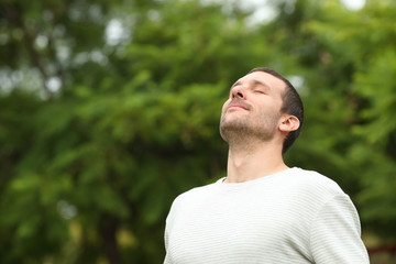 Relaxed adult man breathing fresh air in a forest