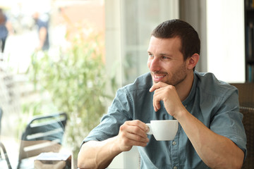 Happy man holding coffee cup looking away through a window