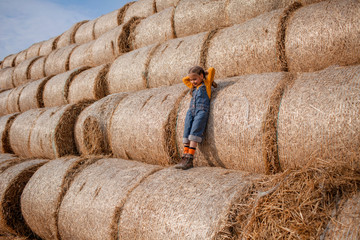 Cute girl having fun on rolls of hay bales in field
