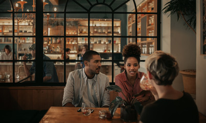 Diverse friends chatting over drinks in a bar at night