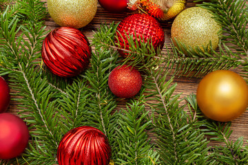 Fur spruce pine coniferous branches, sparkling shiny toys balls on the brown brushed wooden background