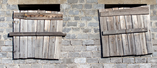The windows of a brick house boarded up with wooden boards