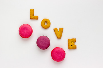 French Pink Macaroons and Love Lettering with Cookies on White Background. Top View Traditional Dessert for Feminine Design. Confectionery, Fashion, Beauty Advertising Template.