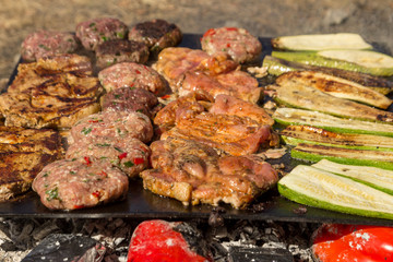 Meat grilled pork with vegetables. Meat balls and steak during grilling. Close up.