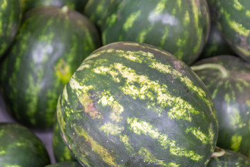 Ripe sugar sweet watermelons at a crates on stand at the marketplace. Selective focus.