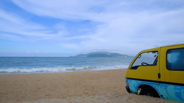 Old van car or vintage classic car parked on the tropical sandy beach. Stock video footage view of sea waves, sand and old retro van car damaged. Leisure trip in the summer season