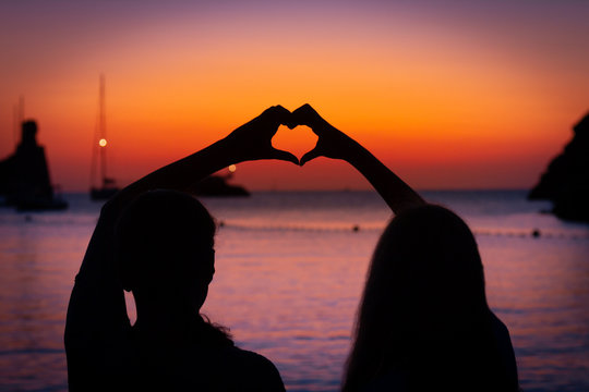 silhouette of two girls at sunset with love